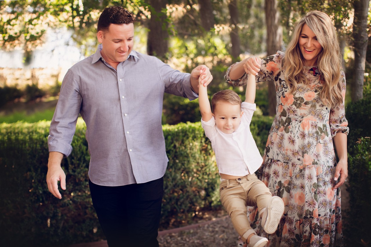 Picture of mom, dad and son swining the son in the air